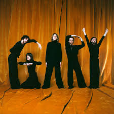 Gary by Blossoms album cover showing five men dressed in black spell out 'Gary' using their bodies in front of a brown backdrop.