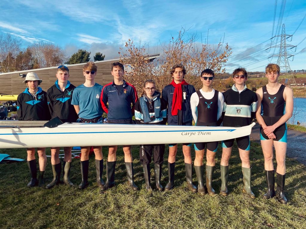 The men's first eight standing behind their boat on the River Tyne