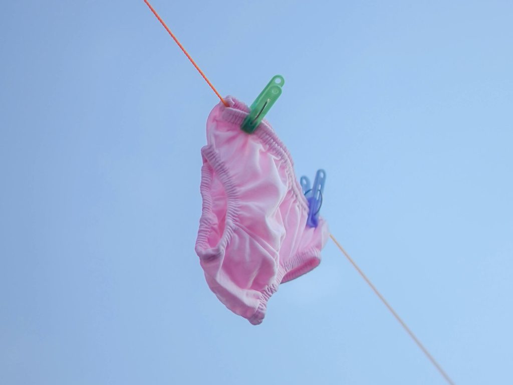 An image of a pair of pink pants on a washing line, against a clear blue sky.
