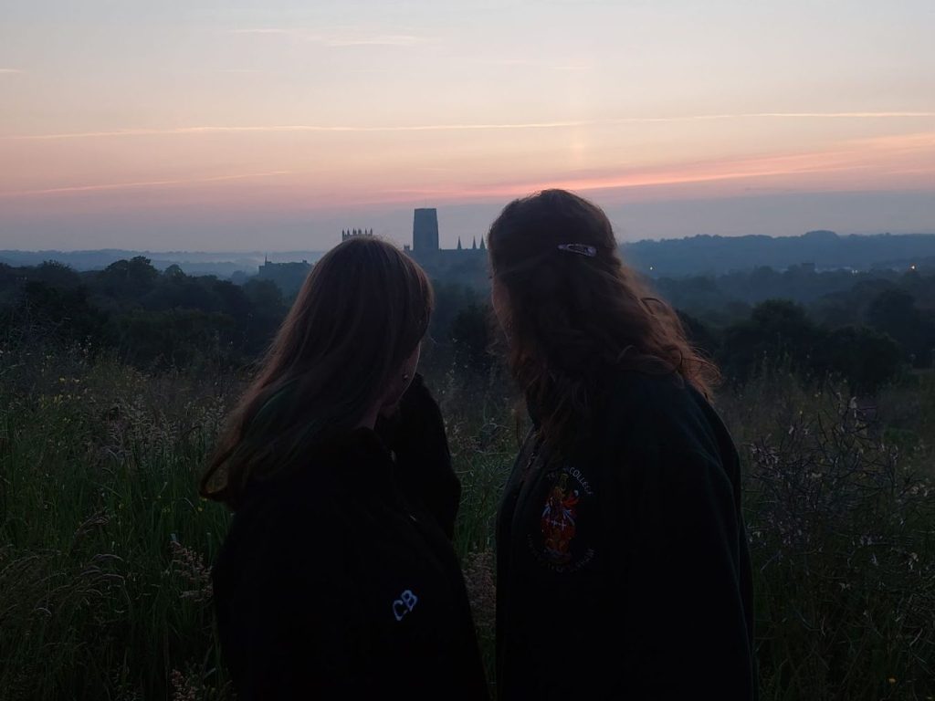 Two girls watch the sunrise over Durham Cathedral