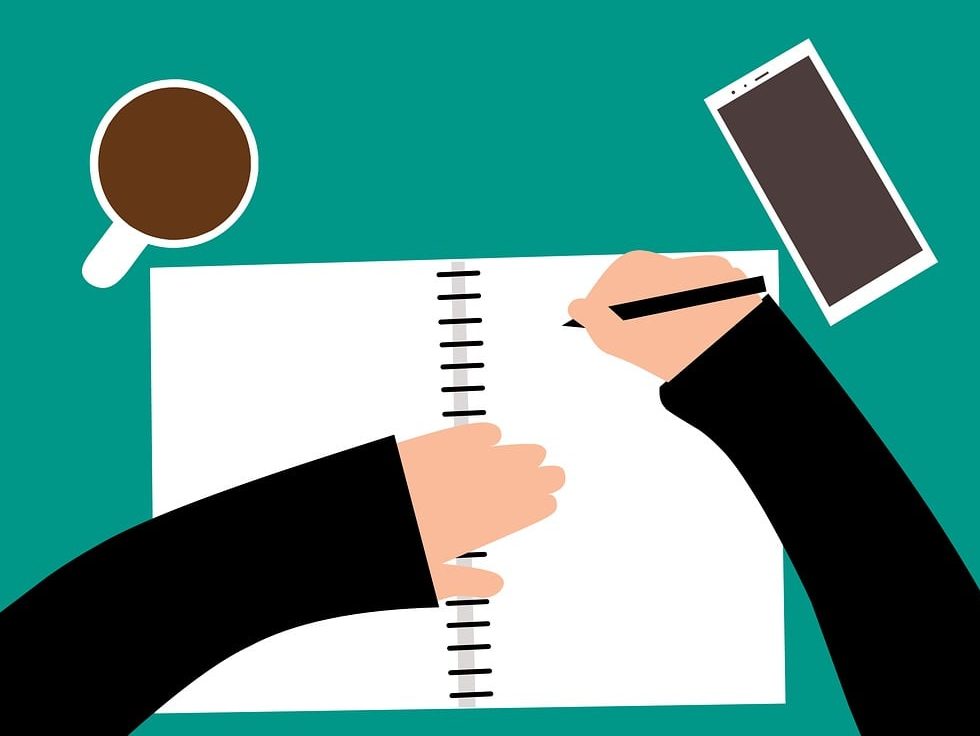 An animated image from the point of view of someone writing in a notebook - we see their arms in a black jumper, a cup of coffee to their left, and a phone to their right