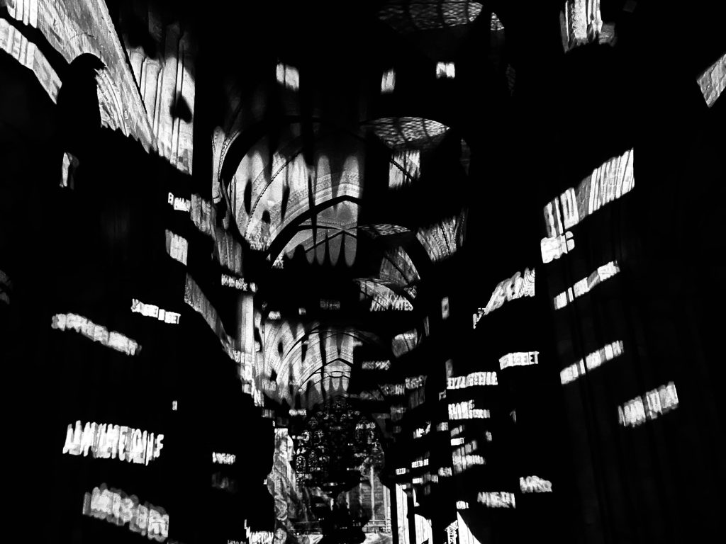 A black and white image of words projected in a chaotic and scrambled manner.