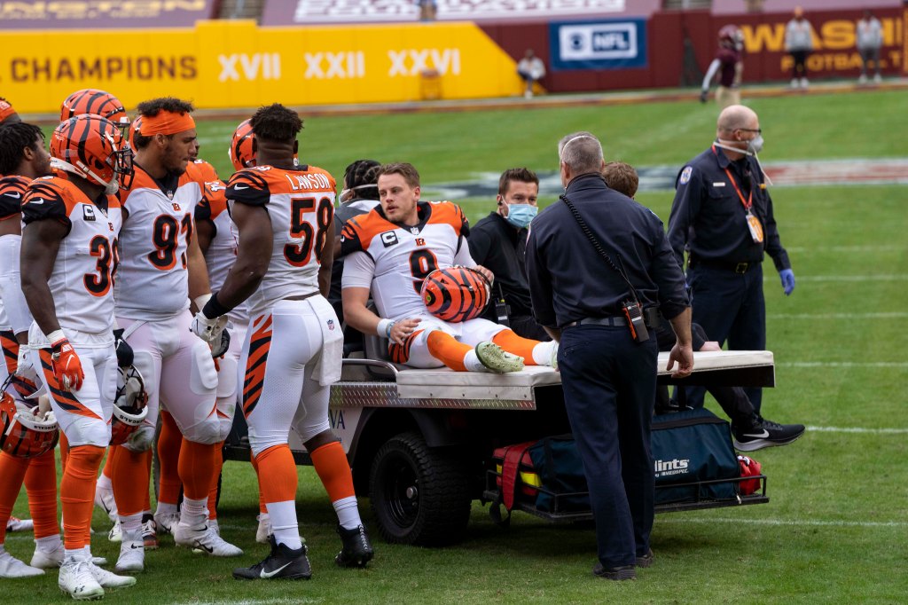 Joe Burrow sitting on a truck after his 2020 injury, surrounded by concerned teammates.