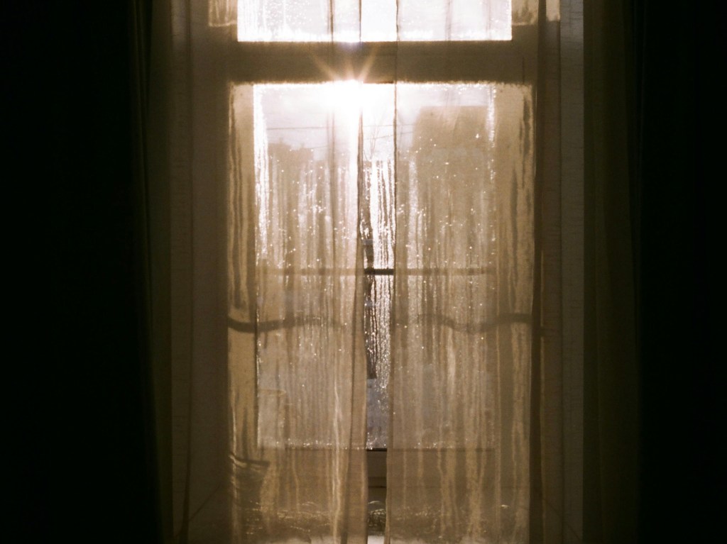 Sunlight shining through a door with curtains