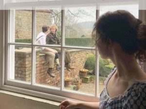 Poster for Lavender featuring a woman looking out a window at two men sitting on a wall.